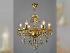 6-arm chandelier made of plated crystal in an amber shade on a light background lit