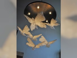 Custom chandelier - butterflies suspended on thin steel ropes under a circular lighting plate