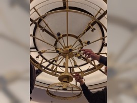 Installation of crystal pendants and chain on the brass structure of the chandelier