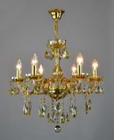 6-arm chandelier made of plated crystal in an amber shade on a light background lit
