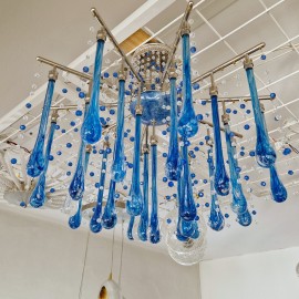 Design variations of modern chandeliers from clear and blue crystal drops reflecting light from ceiling soffits